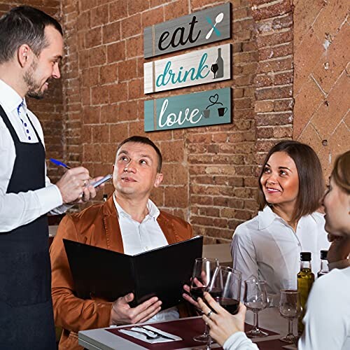 Waiter taking order from a couple in a restaurant with decorative signs in the background.